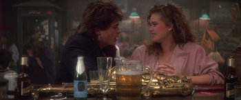 Movie still from “St. Elmo's Fire” (1985), directed by Joel Schumacher – A man and a woman sitting at a table with a beer; Close Up shot, Over the shoulder angle