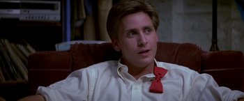 Movie still from “St. Elmo's Fire” (1985), directed by Joel Schumacher – A man wearing a bow tie sitting in a chair; Close Up shot, Over the shoulder angle