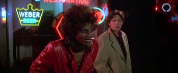 Movie still from “St. Elmo's Fire” (1985), directed by Joel Schumacher – Two people standing in front of a neon sign at night; Close Up shot, Over the shoulder angle