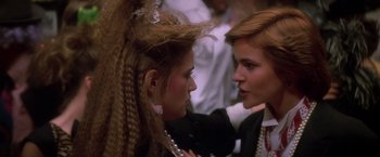 Movie still from “St. Elmo's Fire” (1985), directed by Joel Schumacher – Two women are talking to each other in a crowd of people; Close Up shot, Over the shoulder angle