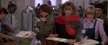 Movie still from “St. Elmo's Fire” (1985), directed by Joel Schumacher – Two women are standing in front of plates of food in a cafeteria; Medium shot, Over the shoulder angle