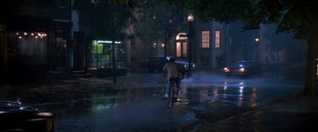 Movie still from “St. Elmo's Fire” (1985), directed by Joel Schumacher – A man riding a bike down a street at night; Extreme Wide shot, High angle