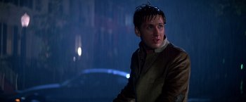 Movie still from “St. Elmo's Fire” (1985), directed by Joel Schumacher – A man in a brown jacket is standing in the rain; Close Up shot, Low angle