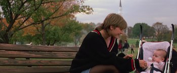 Movie still from “St. Elmo's Fire” (1985), directed by Joel Schumacher – A woman sitting on top of a wooden park bench; Medium shot, Over the shoulder angle