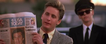 Movie still from “St. Elmo's Fire” (1985), directed by Joel Schumacher – A man in a suit and tie holding a newspaper; Close Up shot, Over the shoulder angle