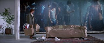 Movie still from “St. Elmo's Fire” (1985), directed by Joel Schumacher – A woman standing in front of a couch with a bunch of trash on the floor; Wide shot, High angle