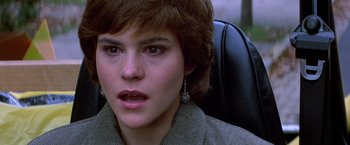 Movie still from “St. Elmo's Fire” (1985), directed by Joel Schumacher – A young woman sitting in a chair with her mouth wide open; Close Up shot, Over the shoulder angle