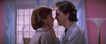 Movie still from “St. Elmo's Fire” (1985), directed by Joel Schumacher – A man and a woman are kissing each other in front of a window; Close Up shot, Low angle