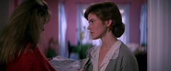 Movie still from “St. Elmo's Fire” (1985), directed by Joel Schumacher – A woman in a gray jacket holding a newspaper; Close Up shot, Over the shoulder angle