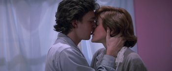 Movie still from “St. Elmo's Fire” (1985), directed by Joel Schumacher – A man and a woman kissing each other in front of a curtain; Close Up shot, Low angle