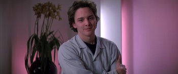 Movie still from “St. Elmo's Fire” (1985), directed by Joel Schumacher – A young man with long hair is posing for a picture; Close Up shot, Low angle