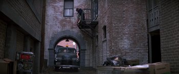 Movie still from “St. Elmo's Fire” (1985), directed by Joel Schumacher – A man standing on a fire escape next to an old truck; Wide shot, Low angle