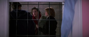 Movie still from “St. Elmo's Fire” (1985), directed by Joel Schumacher – A man and a woman standing next to each other in front of a cage; Medium shot, Over the shoulder angle