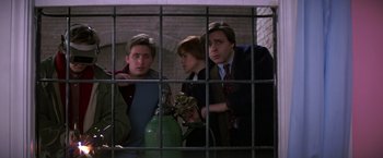 Movie still from “St. Elmo's Fire” (1985), directed by Joel Schumacher – Three young men looking through a cage at a fire hydrant; Medium shot, Low angle