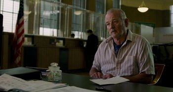 Movie still from “St. Vincent” (2014), directed by Theodore Melfi – An older man sitting at a table with papers in front of him; Medium shot, Over the shoulder angle