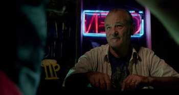 Movie still from “St. Vincent” (2014), directed by Theodore Melfi – An older man sitting at a table in front of a neon sign; Close Up shot, Low angle