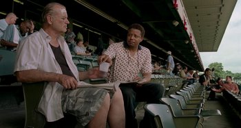 Movie still from “St. Vincent” (2014), directed by Theodore Melfi – Two men are sitting in the stands at a baseball game; Medium shot, Over the shoulder angle