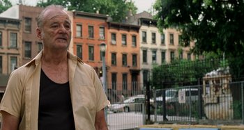 Movie still from “St. Vincent” (2014), directed by Theodore Melfi – An older man standing in front of a row of buildings; Medium shot, Low angle