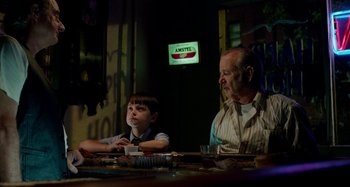 Movie still from “St. Vincent” (2014), directed by Theodore Melfi – A man and a boy sitting at a dinner table; Medium shot, Low angle