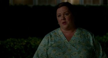 Movie still from “St. Vincent” (2014), directed by Theodore Melfi – A woman in a green floral shirt looking at the camera; Close Up shot, Over the shoulder angle