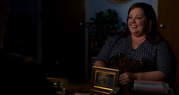 Movie still from “St. Vincent” (2014), directed by Theodore Melfi – A woman sitting at a table with a picture of jesus; Medium shot, Over the shoulder angle