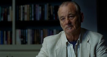 Movie still from “St. Vincent” (2014), directed by Theodore Melfi – A man in a white jacket is sitting in front of a book shelf; Close Up shot, Over the shoulder angle