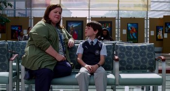 Movie still from “St. Vincent” (2014), directed by Theodore Melfi – A woman sitting next to a young boy in front of a painting; Wide shot, Over the shoulder angle