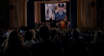 Movie still from “St. Vincent” (2014), directed by Theodore Melfi – A crowd of people in front of a large screen; Wide shot, Over the shoulder angle