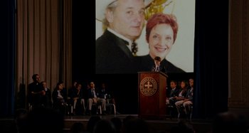 Movie still from “St. Vincent” (2014), directed by Theodore Melfi – A man standing at a podium in front of an audience; Wide shot, Over the shoulder angle