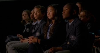 Movie still from “St. Vincent” (2014), directed by Theodore Melfi – A group of young people sitting in a row in front of a black background; Medium shot, High angle
