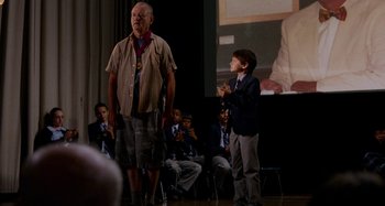Movie still from “St. Vincent” (2014), directed by Theodore Melfi – A man and a boy standing in front of an audience; Medium shot, Over the shoulder angle