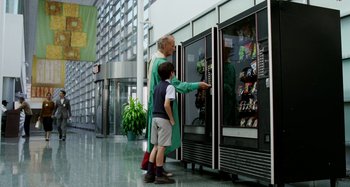 Movie still from “St. Vincent” (2014), directed by Theodore Melfi – A man and a boy are looking at a vending machine; Wide shot, Over the shoulder angle