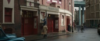 Movie still from “Stan & Ollie” (2018), directed by Jon S. Baird – A man standing in front of a building on the sidewalk; Extreme Wide shot, Low angle