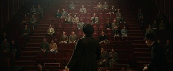 Movie still from “Stan & Ollie” (2018), directed by Jon S. Baird – A group of people sitting in a room with a person standing in front of them; Extreme Wide shot, High angle