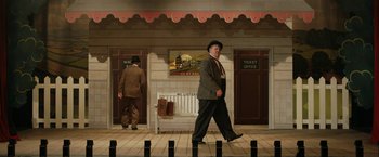 Movie still from “Stan & Ollie” (2018), directed by Jon S. Baird – A painting of a man in a suit and hat walking down a street; Wide shot, Low angle
