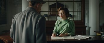 Movie still from “Stan & Ollie” (2018), directed by Jon S. Baird – A woman sitting at a table writing on a piece of paper while an older man looks on; Medium shot, Over the shoulder angle