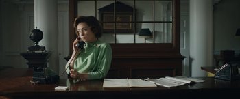Movie still from “Stan & Ollie” (2018), directed by Jon S. Baird – A woman sitting at a table talking on a phone; Medium shot, Low angle