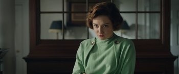 Movie still from “Stan & Ollie” (2018), directed by Jon S. Baird – A woman in a green coat sitting in a room; Medium shot, Over the shoulder angle