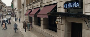 Movie still from “Stan & Ollie” (2018), directed by Jon S. Baird – Two women walk down the sidewalk in front of a building; Extreme Wide shot, Low angle