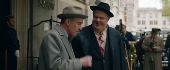 Movie still from “Stan & Ollie” (2018), directed by Jon S. Baird – Two men in suits and hats smoking a cigarette; Medium shot, Over the shoulder angle