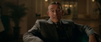 Movie still from “Stan & Ollie” (2018), directed by Jon S. Baird – An older man wearing a suit and tie sitting down; Close Up shot, Over the shoulder angle