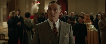 Movie still from “Stan & Ollie” (2018), directed by Jon S. Baird – A man in a suit and tie standing in front of a group of people; Medium shot, Low angle