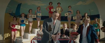 Movie still from “Stan & Ollie” (2018), directed by Jon S. Baird – A man in a suit and tie standing in front of a microphone; Medium shot, Low angle