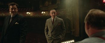 Movie still from “Stan & Ollie” (2018), directed by Jon S. Baird – A man in a suit and tie standing in a theater; Medium shot, Low angle