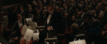 Movie still from “Stan & Ollie” (2018), directed by Jon S. Baird – A man wearing a tuxedo is holding a microphone; Medium shot, High angle