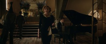 Movie still from “Stan & Ollie” (2018), directed by Jon S. Baird – A woman in a black dress walking in front of a grand piano; Medium shot, Low angle
