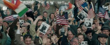 Movie still from “Stan & Ollie” (2018), directed by Jon S. Baird – A group of people holding american flags in the air; Medium shot, High angle