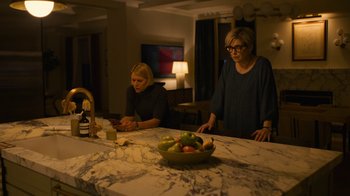 Movie still from “Full Circle” (2023), directed by Steven Soderbergh – Two women sitting at a kitchen counter with a bowl of fruit on the counter; Medium shot, High angle