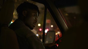 Movie still from “Full Circle” (2023), directed by Steven Soderbergh – A man sitting in the driver's seat of a car at night; Close Up shot, Over the shoulder angle