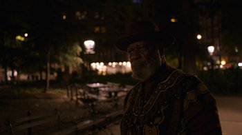 Movie still from “Full Circle” (2023), directed by Steven Soderbergh – An older man with a beard wearing a hat; Medium shot, Over the shoulder angle